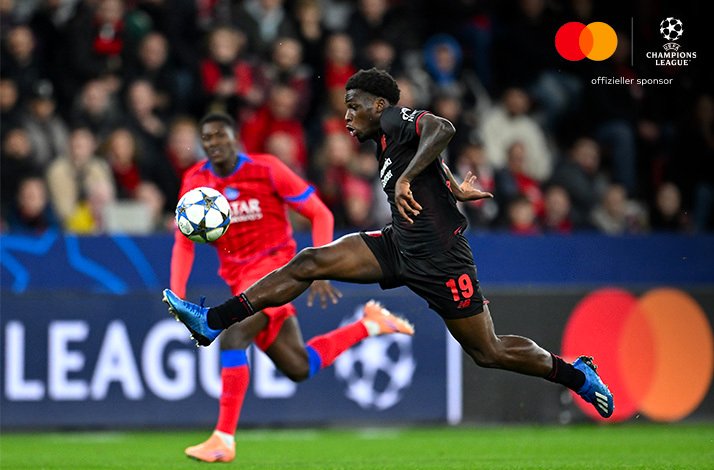 Leverkusen player #19 stretching acrobatically to control the ball during UEFA Champions League 2025/26 match vs PSG.