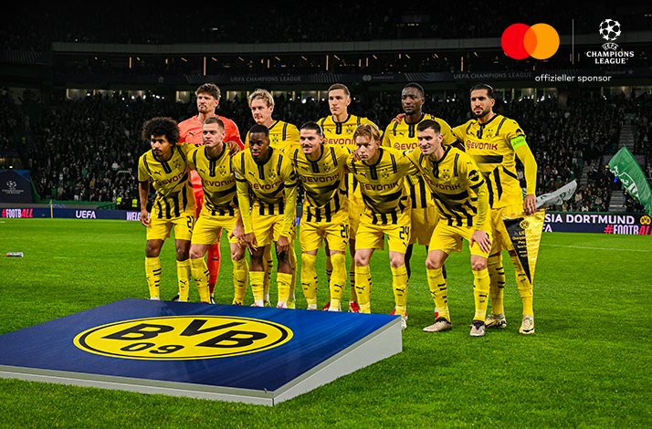 A team of football players posing together for a group photo on the field after a match.