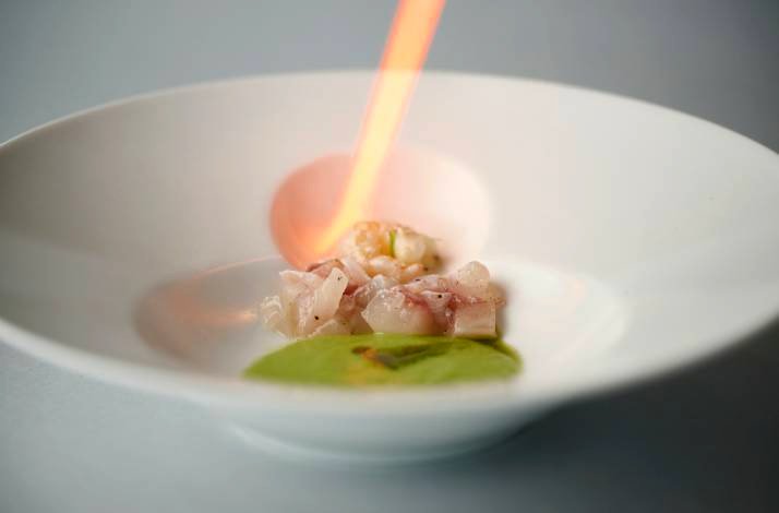 Chef searing fish with a blowtorch.