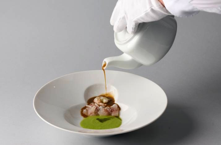 Waiter pouring sauce on a dish.