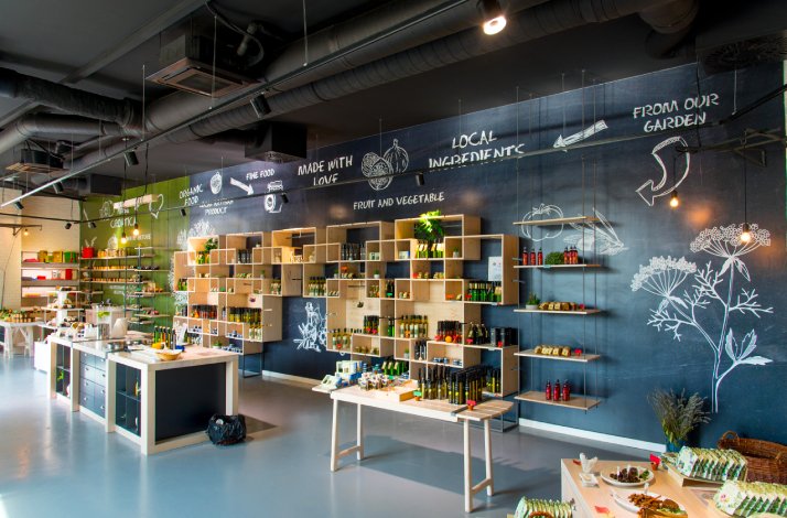 A room in Olive Museum with a counter to cook and food from village garden displayed on shelves.