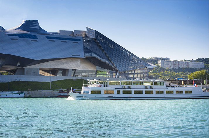 Soak up Lyon's picturesque landscapes on a dining cruise with Les Bateaux Lyonnais: In Lyon, France Cruise boat passing along Confluences Museum at Lyon.
