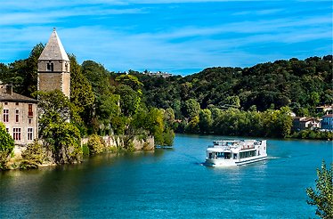 Cruise boat passing along picturesque riverbanks of Lyon.