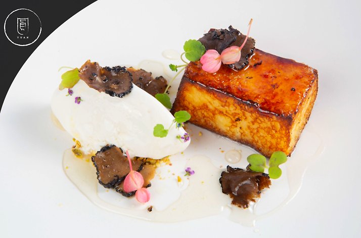 A close up of a dish with truffle and ice cream. Yuan restaurant logo at the upper left corner.