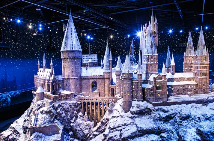 Snowy scale model of a castle set under studio lights, with falling snow effect and blue backdrop.