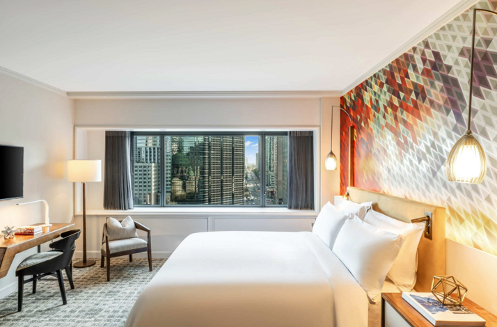 Modern bedroom inside Fairmont Le Reine Elizabeth in Montreal with city views and a colorful geometric accent wall.