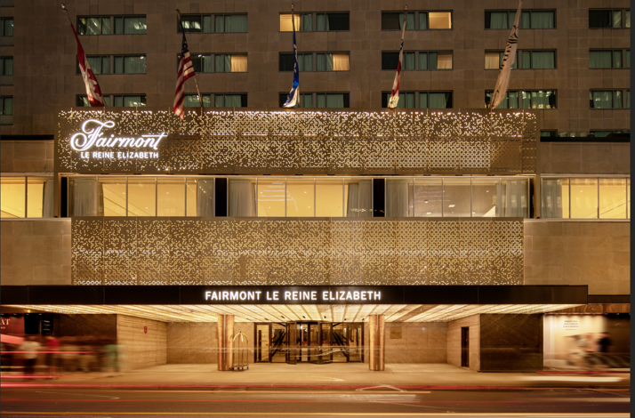 Exterior of Fairmont Le Reine Elizabeth hotel entrance at night with lit gold signage in Montreal, Canada.
