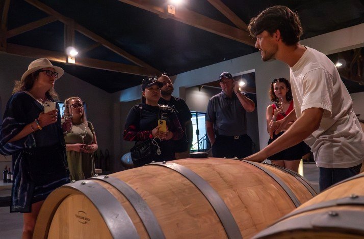 A group of tourists standing in a wine cellar at one of the Bordeaux vineyards. 