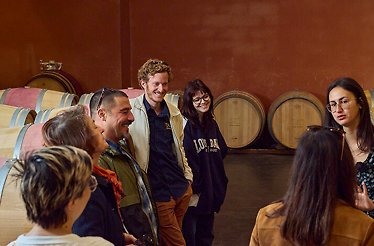 A group of tourists standing in a wine cellar at one of the Bordeaux vineyards. 