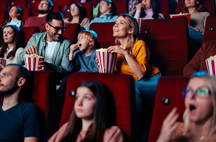 Happy people attending cinema, eating popcorn