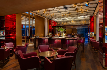 Interior of Republic Bar, featuring red chairs, a central bar, and modern decor.
