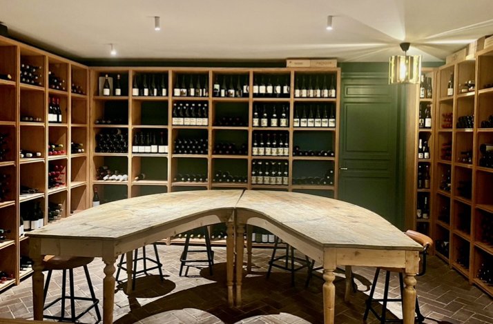 Intimate wine cellar at Club Matador, with wooden racks of bottles surrounding a long tasting table and stools.
