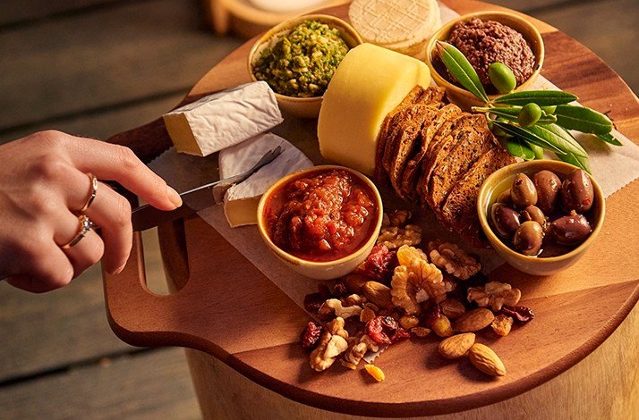 Set of cheese collection with nuts, raisins, sliced bread and olives.