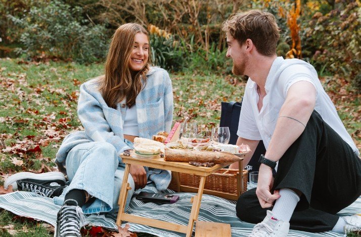 A couple having picnic in the autumn park in Brooklyn, smiling and talking.