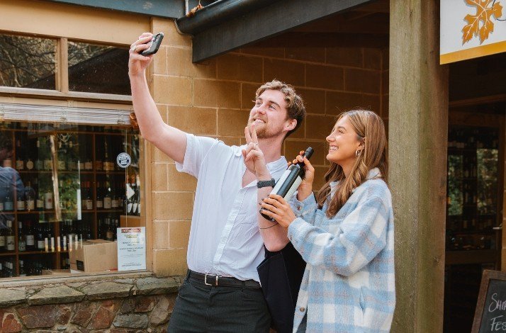 A couple taking a selfie with a bottle of wine.
