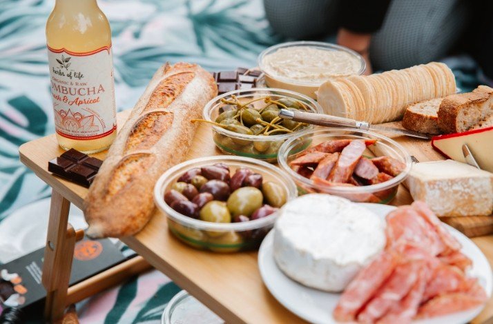 A picnic table served with olives, fresh bread, meat and cheese.