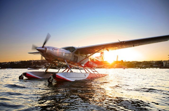 Plane landing on water in the sunset