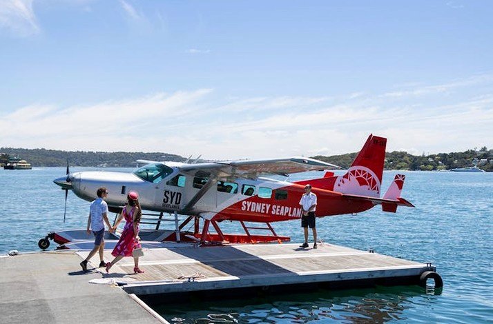 A man and a woman on a bay board Sydney Seaplane guided by the crew member