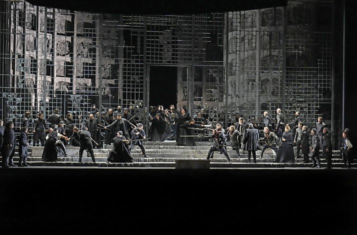Actors interpreting a sword fight live on stage.