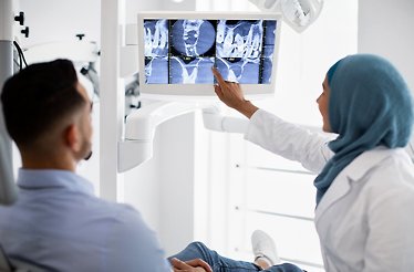 Dentist showing X-ray images of teeth to the patient.