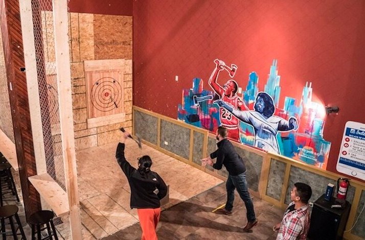 Participants throwing axes at the targets next to the bar of Bad Axe Throwing Chicago.