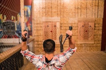 A participant throwing two axes with both hands at the target in Bad Axe Throwing Chicago.