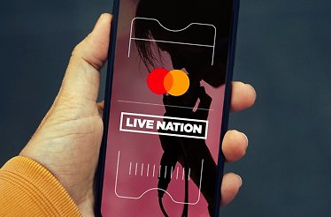 Smartphone held in a hand with screen displaying Live Nation in cooperation with Mastercard.