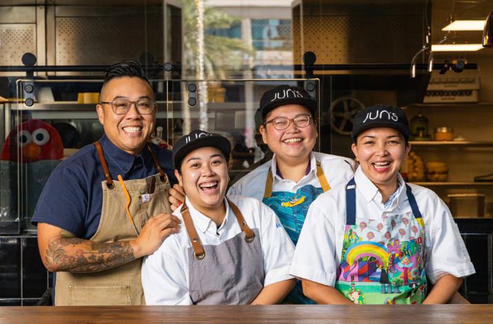 The award-winning Chef Kelvin Cheung is smiling standing in the kitchen with his crew members in Jun's restaurant