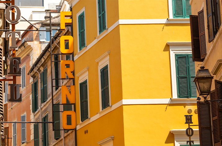 A close-up view of a bright yellow house situated on a narrow street in Rome.