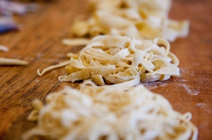 Piles of sliced pasta dough on a wooden table.