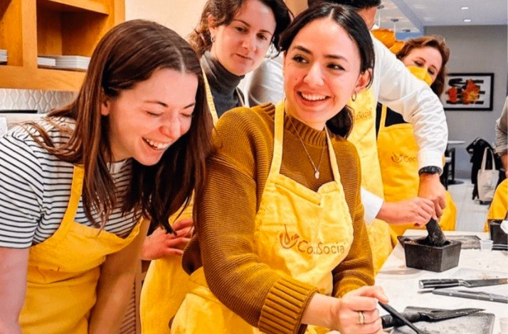 Smiling participants of group cooking class, dressed in yellow aprons