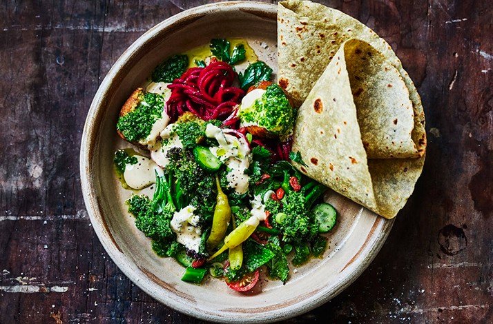 A plate of cooked vegetables and a pita at Naturally Sauced