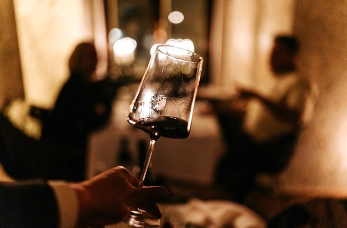 A close-up of man’s hand holding glass of wine.