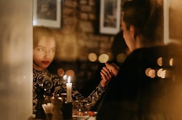 A couple holding hands in dim candlelight during a semi-private dining experience at Da Pino.