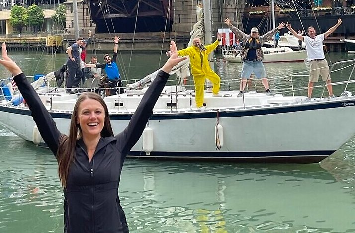 A participant of Chicago River Yoga Walk standing in front of a boat full of people with their hands in the air