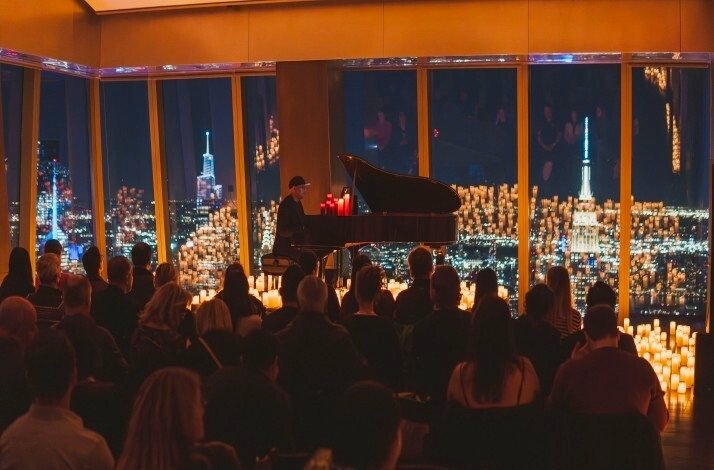 Musician performing with candles overlooking the skyline.
