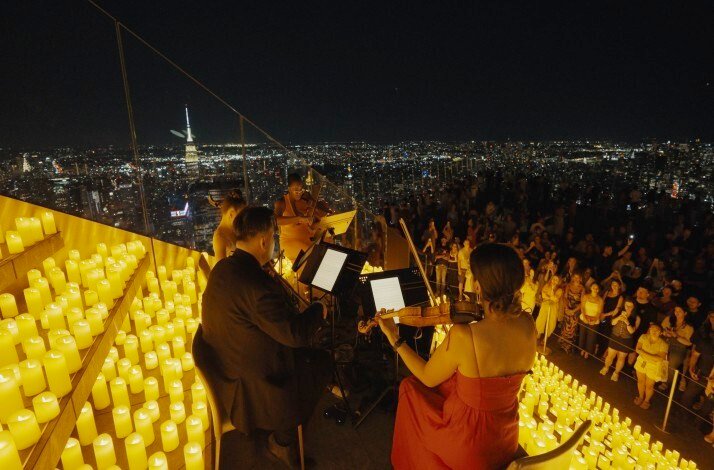 Musicians performing with candles overlooking the skyline.