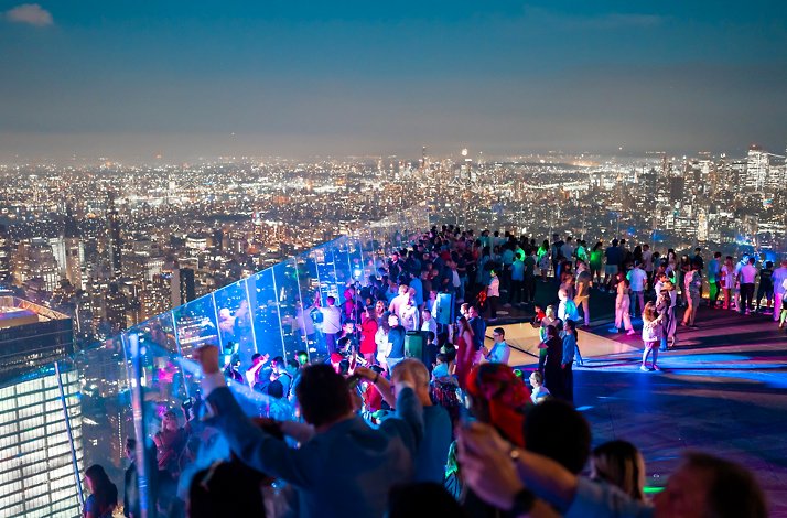 Rooftop crowd enjoying NYC fireworks celebration.