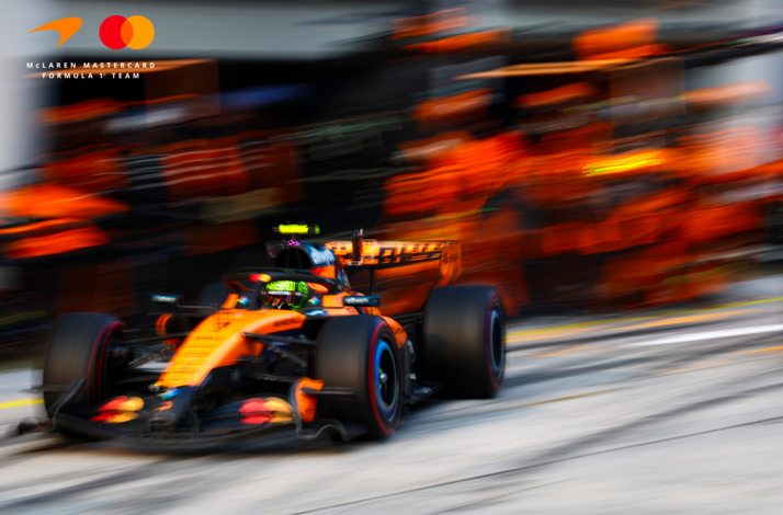 McLaren F1 car speeding on a racetrack captured with motion blur.