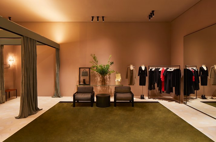 A chic fitting area with soft lighting, velvet curtains, and curated outfits on display.