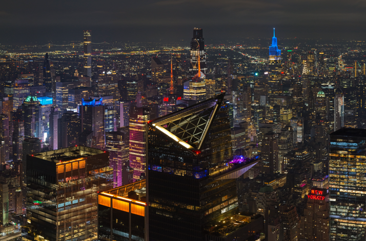NYC skyline at night with Marquee Sky Deck lit up, city lights and iconic buildings visible.
