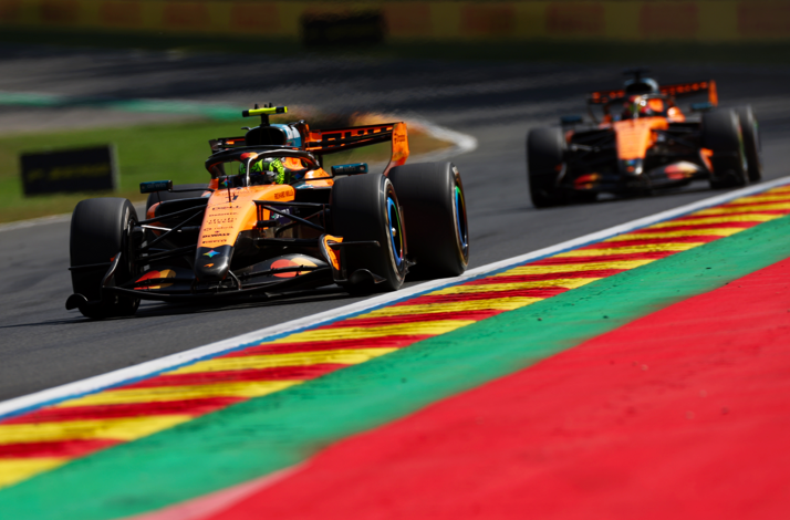 McLaren F1 car accelerating out of a corner with a following car.