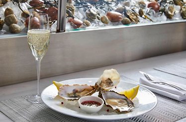 A culinary arrangement showcasing fresh oysters, champagne, and elegant table setting at Estiatorio Milos.