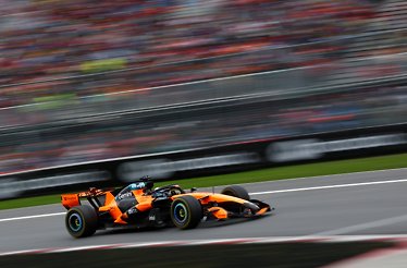 McLaren F1 car speeding on a racetrack captured with motion blur.