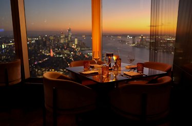 Table at Peak on the 101st floor with NYC skyline at sunset.