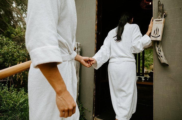 One person leading another to have a calming geothermal bath in Peninsula Hot Springs resort