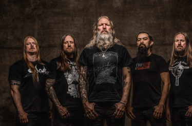 Promotional banner for Amon Amarth The Allfather Awakens Tour 2026, displaying the group members in a bar