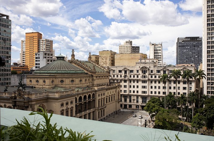 The view from Espaço Priceless rooftop with buildings and palm trees.