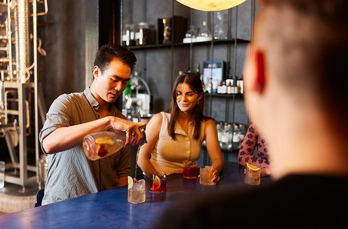 One of the guests pouring a gin cocktail through a strainer.