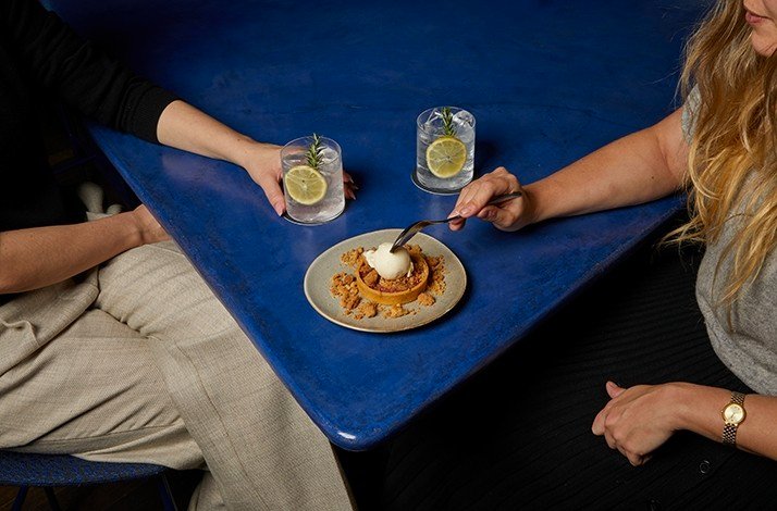 2 people drinking gin cocktails and sharing a dessert.